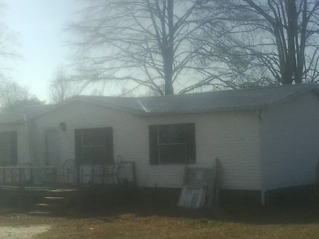 New metal roof on a white painted brick home on a foggy morning in Rogers